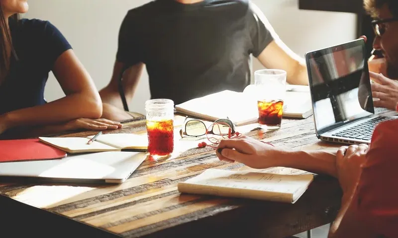 a sunlit desk with hands taking notes and a sense of collaboration in the air