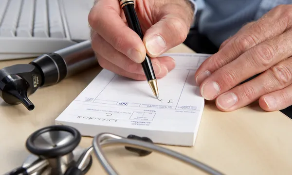 someone writing on a notepad with a stetescope in front of them