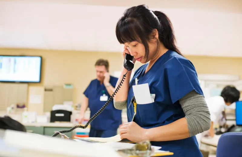 a nurse in blue scrubs talking on the phone