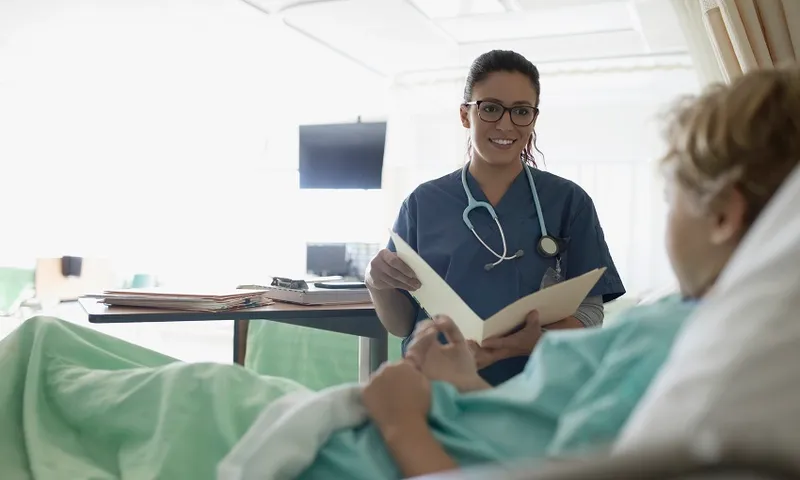 Female nurse with medical record talking to boy patient in hospital