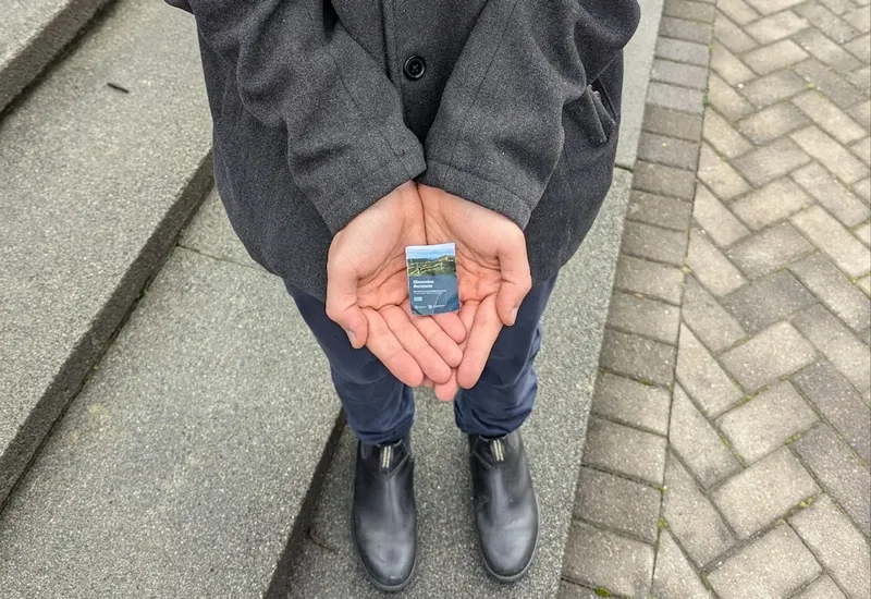 a white person's hand with a very small emissions reduction plan in it