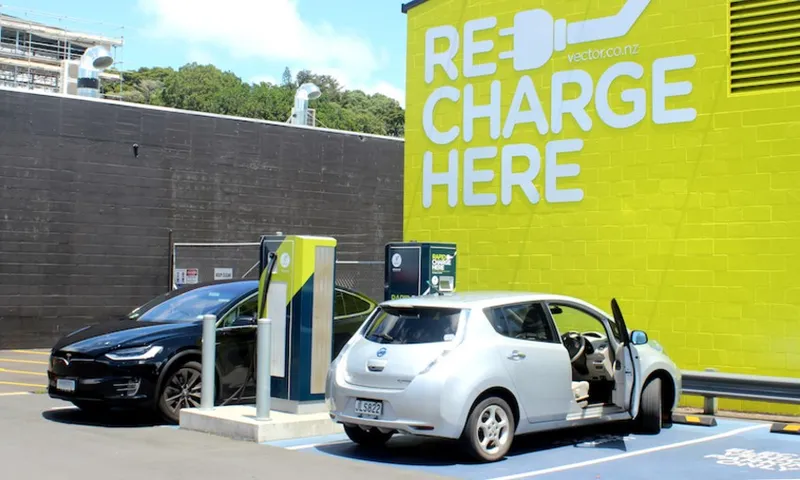 a car with a mural in the bacground reading RECHARGE HERE With a plug illustration