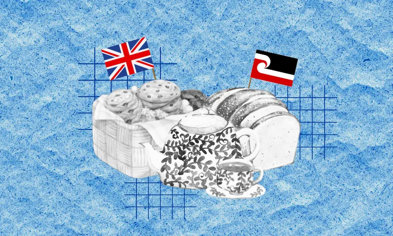 A basket of biscuits with a British flag, tea pot, tea cup, and a loaf of bread with a Māori flag on it.