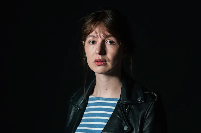 Photograph of a young woman, pale, serious-looking, partly in shadow