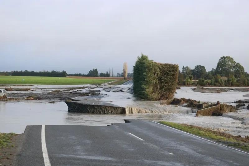 a road lll broken up and covered in water, upended vegetation. something bad has happened here!