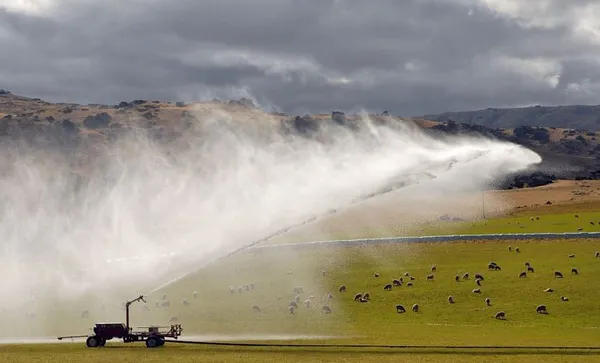 a big irrigator spraying mountain water in the air to try to make the land do something it wouldn't do on its own