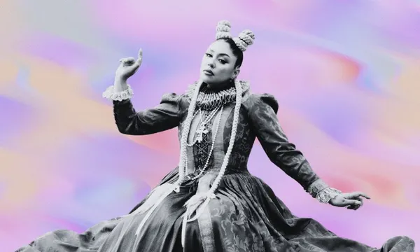 A person wearing an ornate, vintage-style dress with intricate details poses gracefully against a pastel swirl background. The outfit features ruffles and layered necklaces, and the hairstyle includes two buns on top of the head.