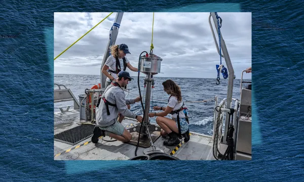 three people work on a cylindrical marine sediment corer