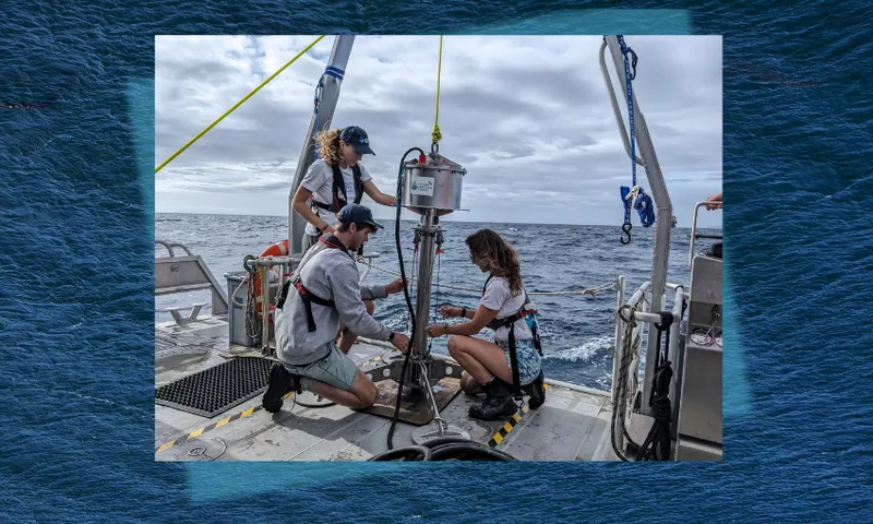 three people work on a cylindrical marine sediment corer