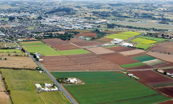 Photograph of Pukekohe from the air that shows some of the rural land and homes around the high density residential areas and town