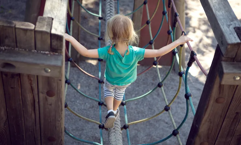 Child (3-4) balancing on climbing frame