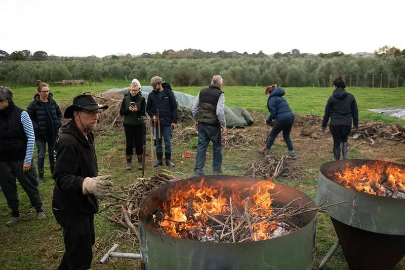 lots of people moving around a fire putting twigs in