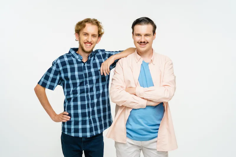 Two friends stand next to each other, smiling at the camera