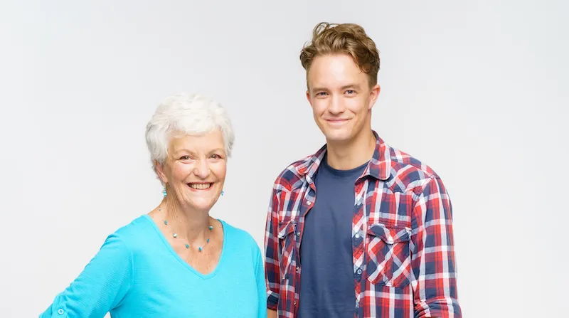 A mother and son stand next to each other and smile at the camera