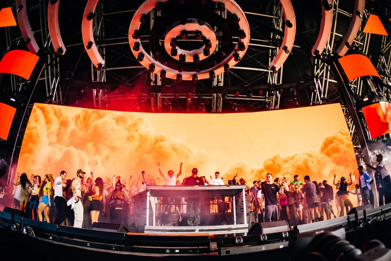 A DJ performs at Coachella on a massive stage packed with happy people.