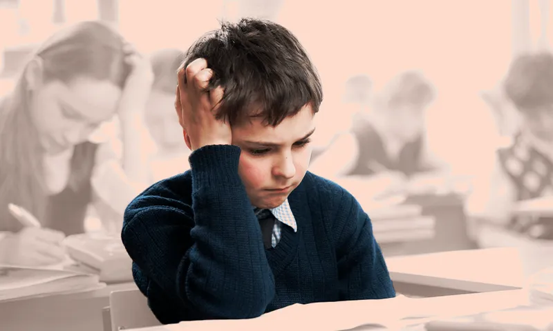 a boy sitting at his desk with his head in his hands