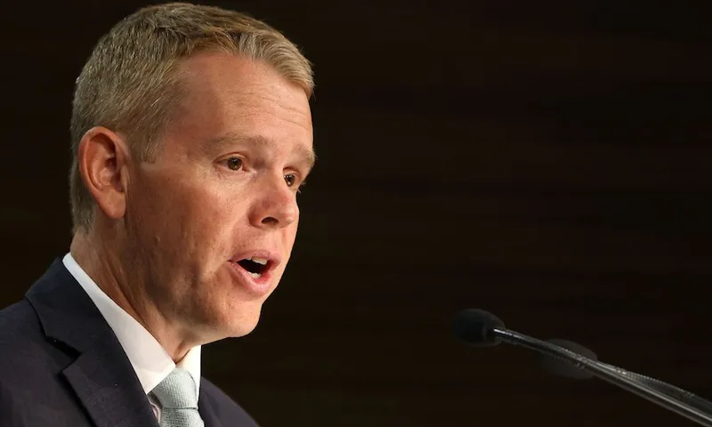 a white man wearing a light teal tie speaking with his mouth open against a black background