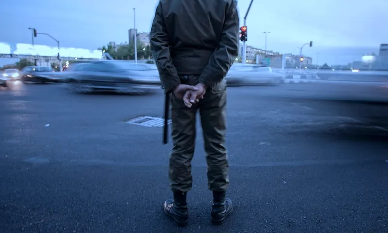 Iranian morality policeman photographed from behind standing guard while monitoring an area in Tehran