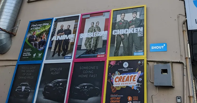 a beige wall with posters of two people in uniform and the words "anime" "chicken" and "bubblegum"