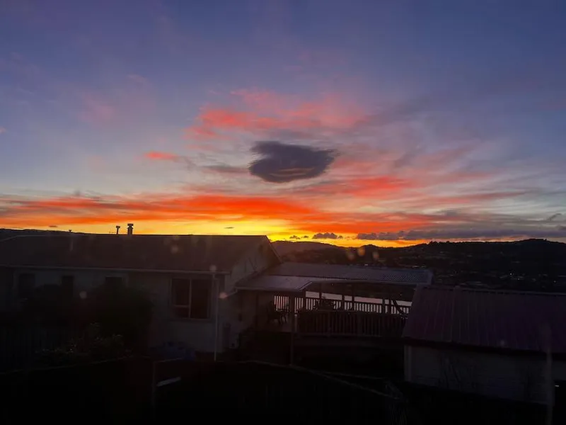 The sun rising above the hills with a with a house in the foreground