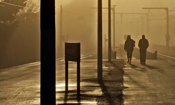 silhouette of two people on a train station platform