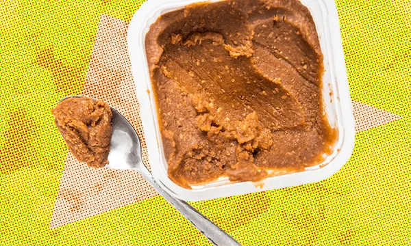 a teaspoon digging into a big tub of miso paste