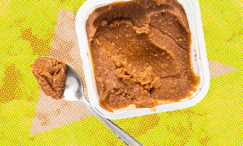 a teaspoon digging into a big tub of miso paste