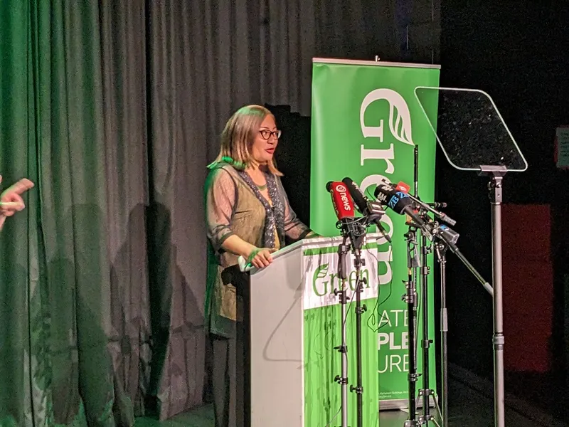 marama davidson wearing green standing at a lectern