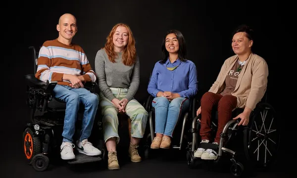 Red Nicholson (wheelchair-user), Beth Awatere, Olivia Shivas (wheelchair-user) and Tania Bissett (wheelchair-user) smile towards with camera and post against a black background. Credit: Curative