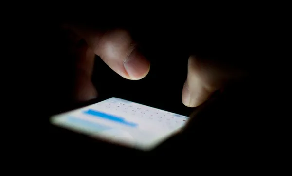 Cropped Hands Typing On Mobile Phone In Dark