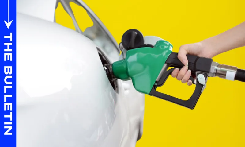 A person’s hand holds a green gasoline pump nozzle, fueling a white car against a bright yellow background. A blue vertical banner on the left reads "THE BULLETIN.