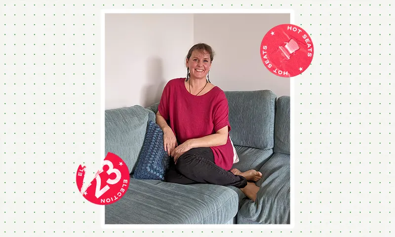 a woman wearing a red shirt sitting on a blue couch with a smile and a election 2023 spinoff logo on top