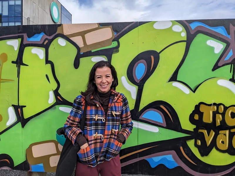 a woman smiling in front of a graffiti wall