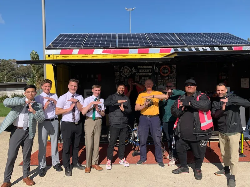 Mormon missionaries, Triple Teez kaimahi and AT staff pull a T outside the Māngere bike hub.