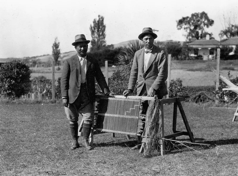 a black and white picture of two men wtahnding ina field and wearing suits