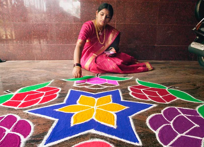 Padma, 18, gives finishes touches to a "rangoli",