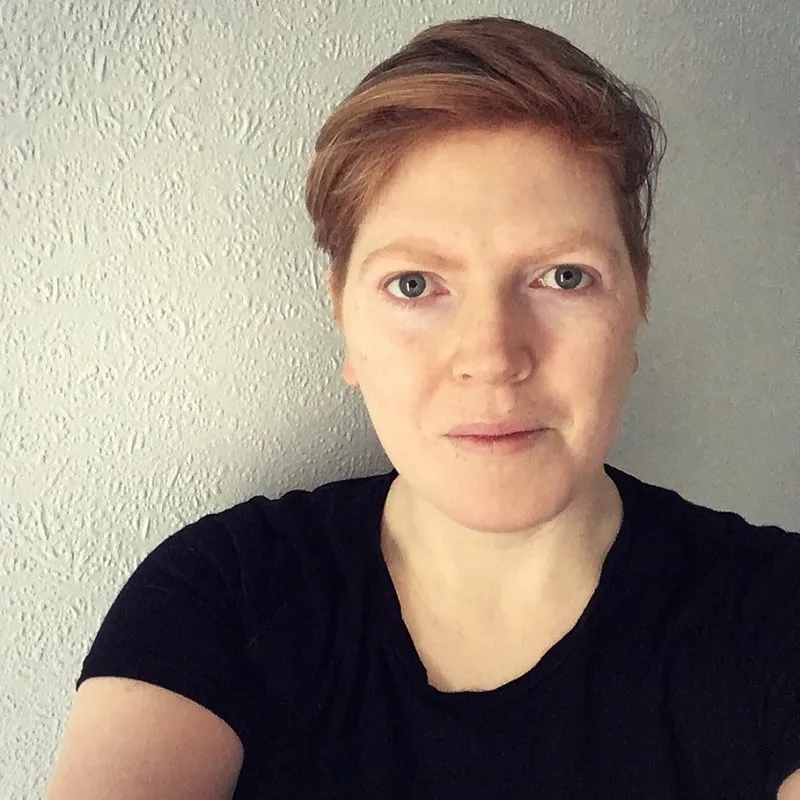 a woman with short red hair and a black tshirt smiling at the camera