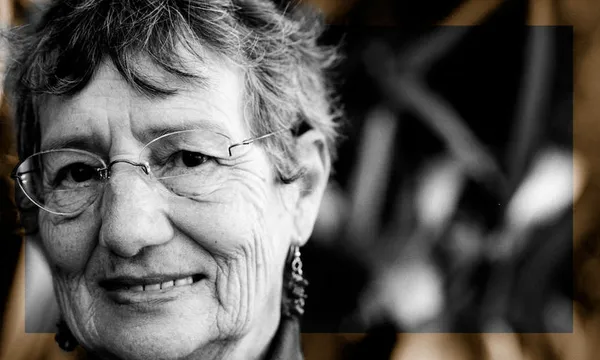 Black and white portrait of an older woman wearing glasses, looking straight to camera with an assessing sort of air