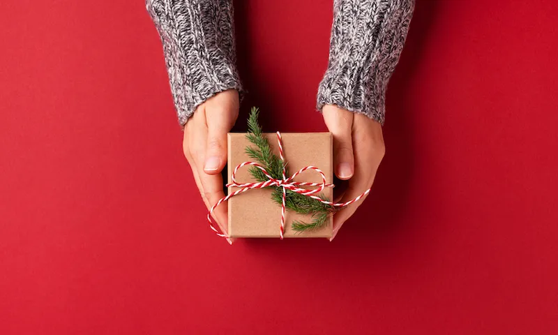 a red background with hhands holding a wrapped present