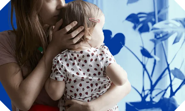 A young woman holds a baby looking out the window. They are in colour but the surrounding room is blue.