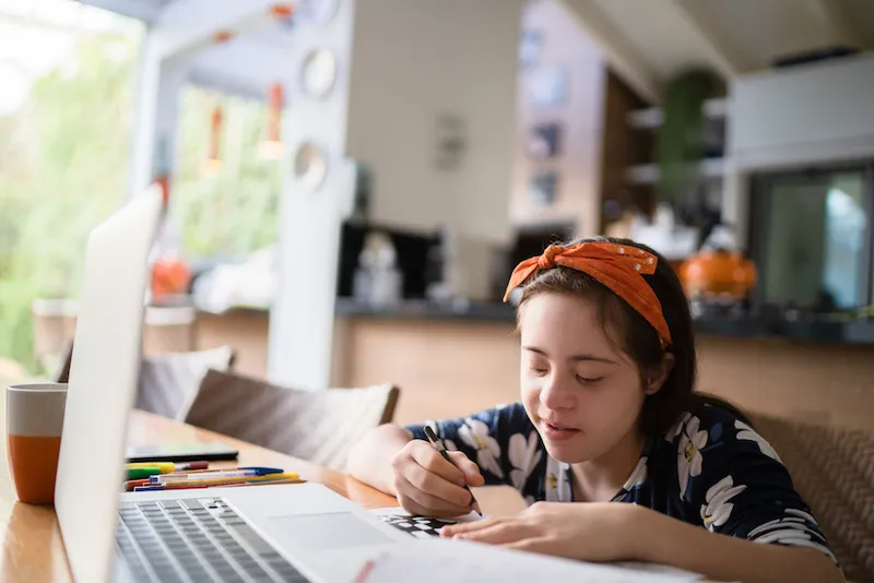 Special needs girl studying using laptop at home