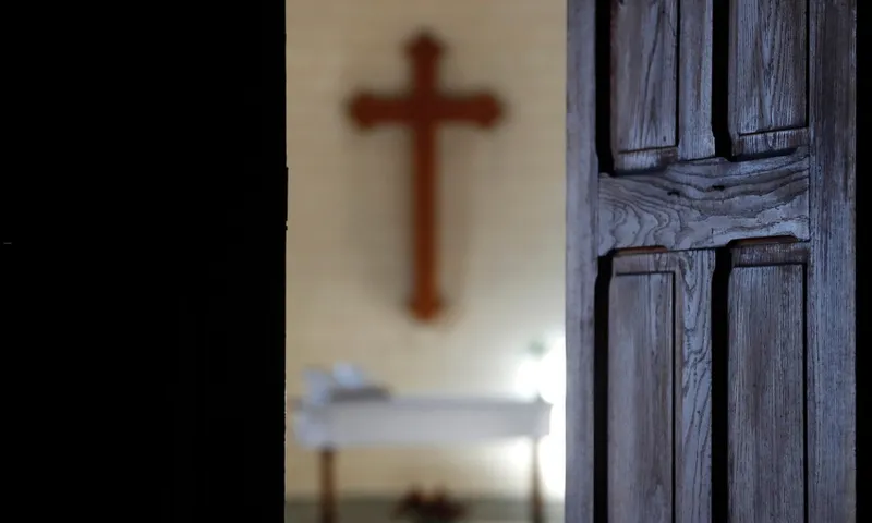 A open door in a church showing a cross in the background