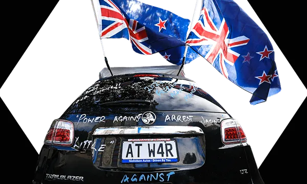 Car parked near parliament in Wellington decorated with upside down flags and a number plate saying "At War"