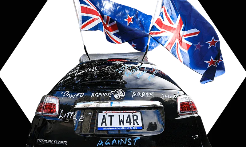 Car parked near parliament in Wellington decorated with upside down flags and a number plate saying "At War"