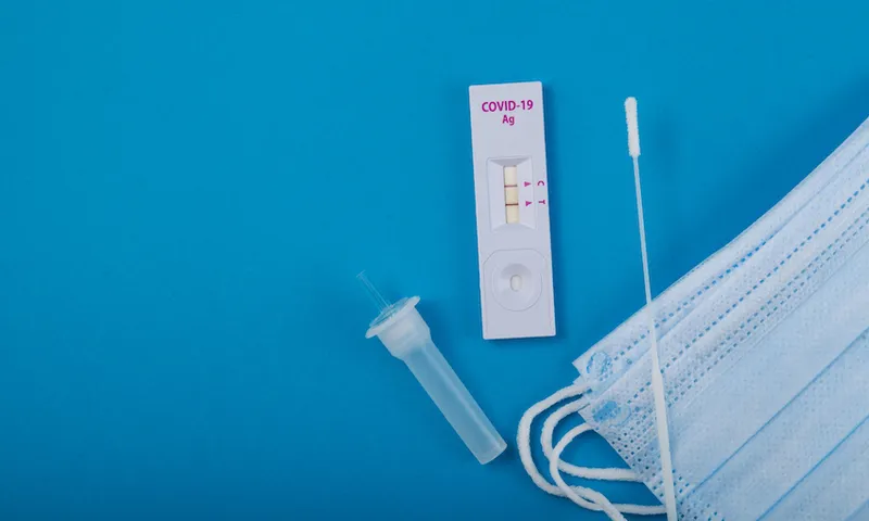 Rapid test for Covid-19 Coronavirus, positive result. Laboratory kit for self-testing at home. Blue paper background, copy space