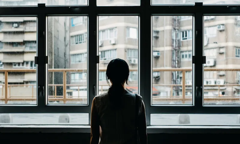 Rear view of woman looking out to city through window