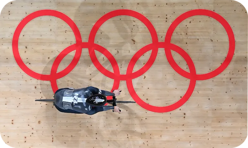 overhead view of a cyclist on a track printed with the Olympic rings