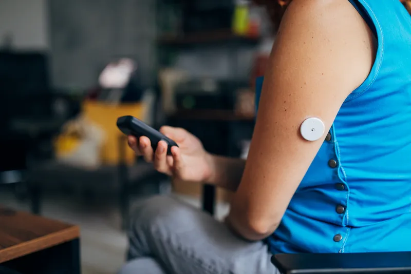 Woman with type 1 diabetes, analyzing the result on her continuous glucose monitor, to see if she needs a dose of insulin