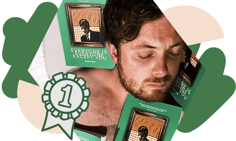 Photo of a young, bearded man, sleeping topless nestled into copies of his book of poetry.
