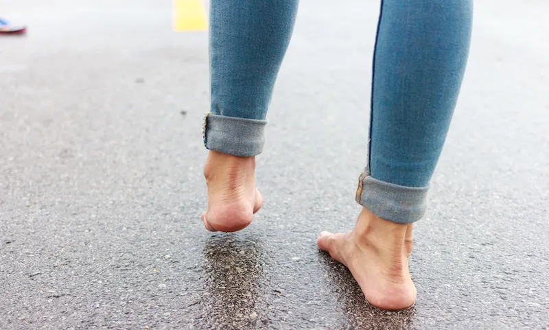 Low Section Of Woman Standing On Wet Road